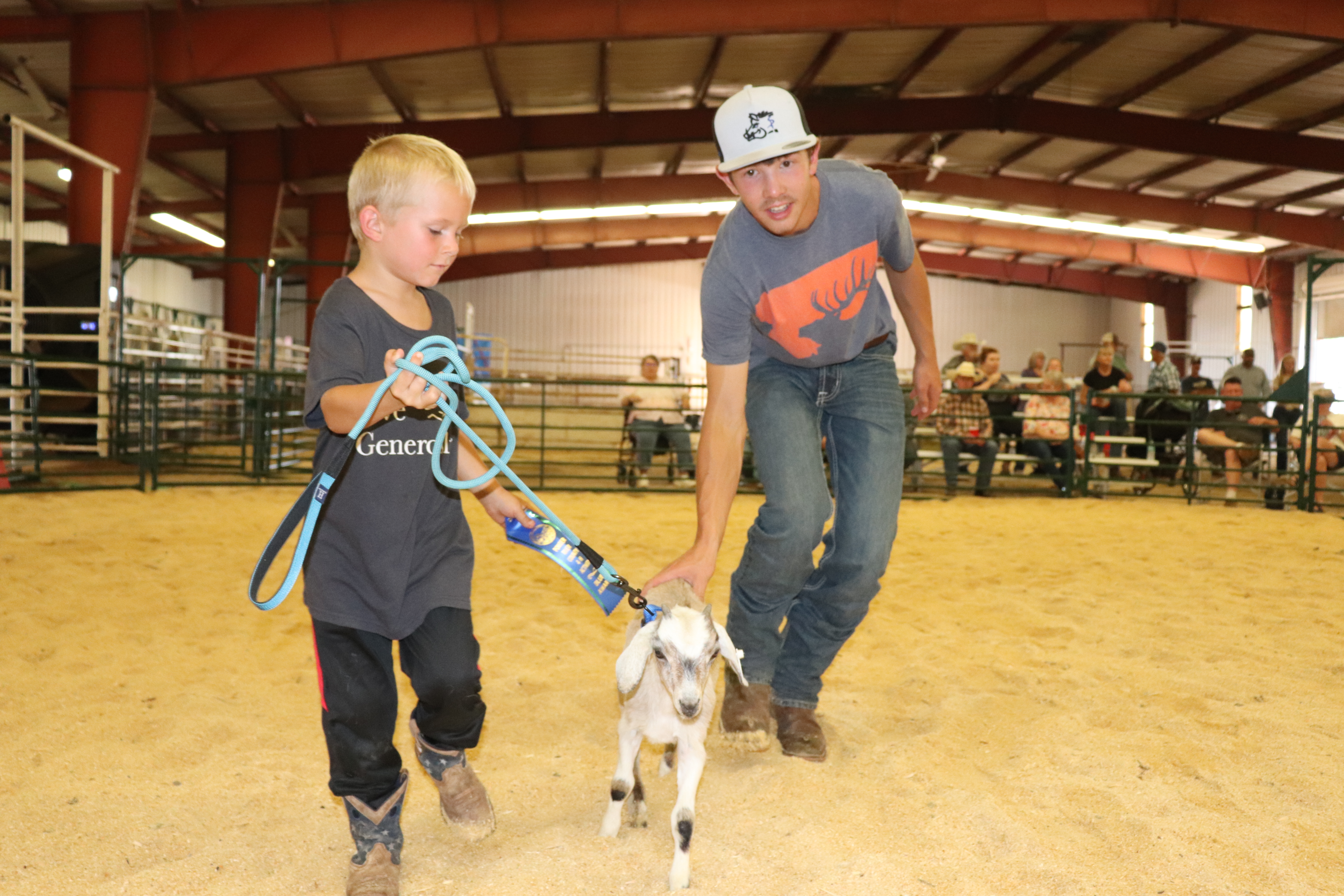 Teen 4-H member Darren VerWolf assists Lincoln Ostendorf during the bum show with his kid Milkshake.